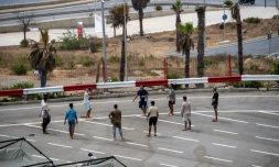 Des migrants jouent au foot sur un parking près d'abris temporaires installés pour eux, le 27 août 2026 à Ceuta