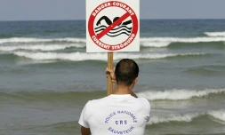 Un CRS maître-nageur-sauveteur installe un panneau indiquant la présence de courants de baïne, le 21 juillet 2004 sur la plage de Lacanau  