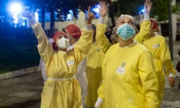 Des personnels soignants saluent les personnes qui les applaudissent devant l'HĂŽpital de Barcelone, le 13 avril 2020 en Espagne