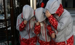 Des volontaires tiennent leurs capuches à cause des vents violents à l'extérieur de la patinoire Arena de Gangneung, le 15 février 2018