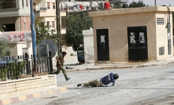Sammy Ketz, grand reporter à l'AFP, à terre pendant des échanges de tirs dans la ville de Maaloula en Syrie, alors qu'un militaire syrien traverse en courant, le 18 septembre 2013