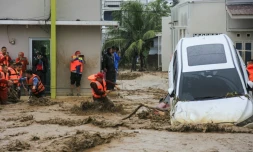 Des sauveteurs tentent d'évacuer des habitants piégés dans leur maison à Padang, dans la province indonésienne de Sumatra Ouest, le 27 novembre 2025