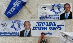 Une femme parle au téléphone, adossée à un mur couvert d'affiches électorales soutenant le Premier ministre Benjamin Netanyahu, à Beersheva, dans le sud d'Israël, le 15 septembre 2019