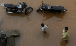 Des passants sur une route détrempée aprÚs de fortes pluies liées au cyclone Nivar, à Pondichéry en Inde le 26 novembre 2020