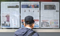 Un homme lit un article de journal, affiché dans une vitrine, consacré à la décision de la Corée du Nord d'envoyer des troupes pour soutenir Moscou dans sa guerre contre l'Ukraine, à Séoul le 21 octobre 2024