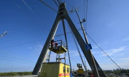 Des techniciens réparent une ligne électrique de trolleybus à proximité des dégâts constatés sur un pilier du pont, à la suite d’une attaque de drone contre le pont du Nord à Kiev, le 3 octobre 2026