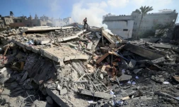 Un membre de la défense civile palestinienne au milieu des décombres d'un bâtiment de la ville de Gaza qui abritait la banque Intaj liée au mouvement Hamas qui contrôle la bande de Gaza, le 15 mai 2021