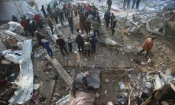 Des Palestiniens rassemblés sur les lieux d'une frappe israélienne qui a touché une école abritant des déplacés, à Gaza-ville le 15 janvier 2025