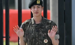 Jin, membre du boys band BTS, fait un signe aprÚs avoir été libéré de son service militaire obligatoire devant le camp d'entraßnement de Yeoncheon, en Corée du Sud, le 12 juin 2024