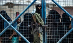 Un combattant des forces kurdes en faction devant une porte du camp d'Al-Hol, dans le nord-est de la Syrie, le 15 juillet 2021