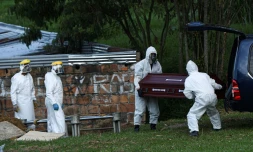 Le personnel d'un cimetiÚre à Medellin en Colombie enterrent le cercueil d'une femme décédée du Covid-19 le 12 août 2020
