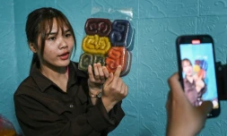 La TikTokeuse Vi Thi Anh tient un sac de nouilles pendant qu'elle filme une vidéo dans son atelier dans la province de Bac Giang, le 7 novembre 2023 au Vietnam