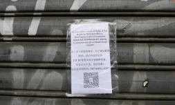Une affiche annonce la fermeture d'un magasin en raison de l'épidémie de nouveau coronavirus en Italie, le 25 février 2020 dans le quartier chinois de Milan