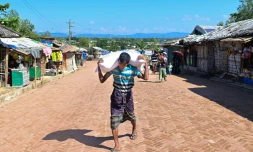 Un réfugié rohingya transporte un sac d'aide alimentaire au camp de Kutupalong, le 23 novembre 2023 au Bangladesh