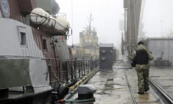 Un soldat ukrainien patrouille prĂšs de navires militaires au mouillage dans le port de Marioupol, le 27 novembre 2018 en Ukraine