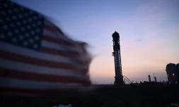 Un drapeau amércain flottant au vent, avec en arrière plan la fusée de SpaceX Starship debout sur son pas de tir à Boca Chica au Texas, le 18 avril 2023