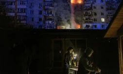 Des gens passent devant des magasins endommagés prÚs d'un immeuble résidentiel en feu à la suite d'une attaque de drones russes sur la ville de Vychhorod, dans la banlieue de Kiev, tÎt le matin du 30 novembre 2025