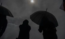 Des personnes observent sous la pluie l'éclipse solaire depuis les rives du lac Villarrica à Pucon, au sud du Chili, le 14 décembre 2020