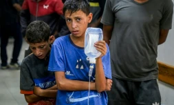 Un jeune palestinien tient une perfusion pour un homme blessé à l'hôpital Nasser, à Khan Younès, dans le sud de la bande de Gaza, le 20 juillet 2025