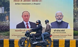 Un motard passe devant des portraits du président russe Vladimir Poutinen, à gauche, et du Premier ministre indien Narendra Modi, à droite, à New Delhi le 4 décembre 2025