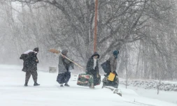 Des habitants marchent sous la neige avec leurs effets personnels sur une route de dans la province afghane de Parwan, dans l'est du pays, le 21 janvier 2026 