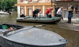 Des membres des forces de sécurité ukrainiennes évacuent des habitants d'une zone inondée à Kherson, le 8 juin 2023, après la destruction partielle du barrage de Kakhovka