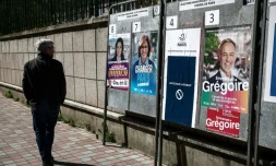 Une personne passe devant des affiches électorales pour les municipales, le 18 mars 2026 à Paris