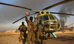 Des combattants antirégime devant  un hélicoptère de l'armée sur le tarmac de l'aérodrome militaire de Nayrab dans la ville d'Alep, dans le nord de la Syrie, le 2 décembre 2024