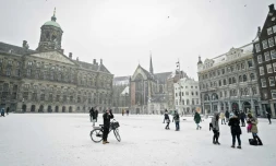Des piétons traversent la place du Dam couverte de neige, le 7 février 2021 à Amsterdam