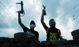 Des manifestants contre le gouvernement brandissent leurs armes artisanales derrière une barricade à Managua, le 20 juin 2018