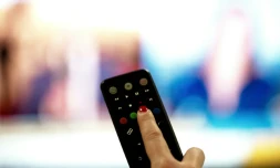 Une personne tient une télécommande pointée vers un écran de télévision, à Paris le 15 janvier 2025
