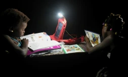 Des écolières ivoiriennes font leurs devoirs grâce à une lampe alimentée par la batterie solaire de leur cartable, le 16 septembre à Rubino, en Côte d'Ivoire