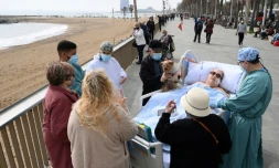 Une patiente hospitalisée à l'hÎpital del Mar à Barcelone est sortie par des amis et du personnel médical pour prendre l'air prÚs d'une plage, à Barcelone, le 4 mars 2021.