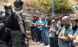 Des soldats israéliens montent la garde alors que des palestiniens prient dans la rue, près de la vieille ville de Jérusalem, le 21 juillet 2017