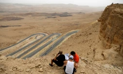 Des touristes assis au bord du "cratère" de Ramon, dans le désert du Néguev en Israël, le 6 mai 2018
