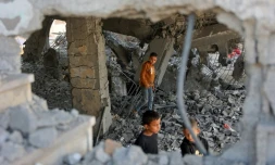 Des garçons marchent parmi les décombres d’un bâtiment endommagé, qui abritait des personnes déplacées dans le quartier de Zeitoun, à Gaza-Ville, le 20 novembre 2025, au lendemain d'une frappe israélienne