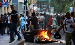 De manifestants marchent prĂšs d'une poubelle en feu durant des affrontements avec la police Ă Marseille, le 1er juillet 2023