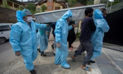 Des proches revĂȘtus de combinaisons de protection portent le corps d'une victime du coronavirus lors de funĂ©railles Ă Srinagar, Inde, le 7 mai 2021