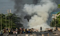 Des manifestants opposés au coup d'Etat militaire derrière une barricade lors de heurts avec les forces de police, le 16 mazrs 2021 à Rangoun, en Birmanie