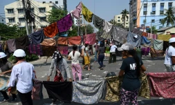 Des longyi, jupes traditionnelles des femmes birmanes, barrent une rue Ă Rangoun, le 3 mars 2021, pour empĂȘcher l'avancĂ©e des soldats. Une superstition birmane veut que les hommes ne doivent pas s'approcher des vĂȘtements de femme, sous peine de perdre leur force