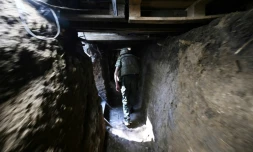 Un soldat ukrainien marche dans une tranchée creusée face à l'armée russe près de la ville de Mikolaïv, dans le sud de l'Ukraine, le 12 juin 2022
