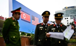 Des policiers vietnamiens devant les drapeaux nord-coréen et américain sur une affiche annonçant le prochain sommet entre les deux dirigeants, le 24 février 2019 à Hanoï