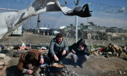 Des migrants font cuire des pommes de terre dans un camp de réfugiés à la frontière entre la Grèce et la Macédoine à Idomeni, le 19 mars 2016