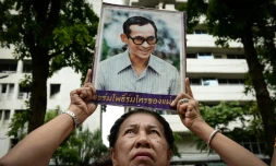 Une Thaïlandaise brandit le portrait du roi de Thaïlande Bhumibol Adulyadej et prie pour son rétablissement devant l'hôpital de Bangkok, où le souverain est soigné, le 12 octobre 2016