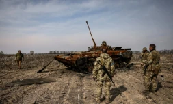 Des soldats ukrainiens se tiennent prÚs d'un tank russe calciné le 31 mars 2022 dans la banlieue de Kiev