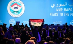 Un homme brandit un drapeau de l'opposition syrienne devant des délégués attendant l'ouverture de la réunion du CongrÚs du dialogue national syrien organisé à Sotchi par Moscou, le 30 janvier 2018