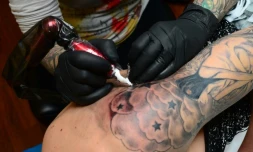 La tatoueuse Corinne Dubosque (L) travaille sur le bras de Timothée, 18 ans, dans son atelier Paradise Tattoo à Plessis Trevise dans la banlieue de Paris, le 9 février 2016