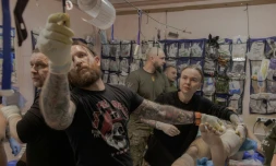 Anastassia Podobailo (d), son collègue et époux Mykola Iassinenko (2e g) et d'autres médecins militaires, soignent un soldat blessé dans un poste médical de la 56e brigade, dans la région de Donetsk, le 15 mars 2026 en Ukraine