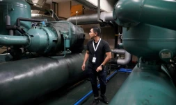 Un technicien de la société Recoolit travaille à capturer les gaz de refroidissemen d'une grande unité de climatisation au sous-sol d'un complexe d'habitation à Jakarta, le 10 juin 2025 en Indonésie 