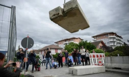 Journalistes et passants observent l'opération de retrait d'un bloc de béton qui fermait la frontiÚre entre France et Suisse, le 14 juin 2020 à Thonex, en France